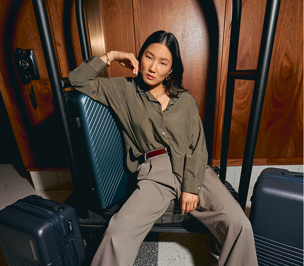 Woman sitting on a suitcase in a wooden interior setting